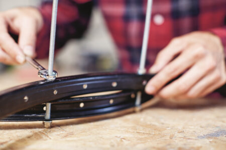 man using wrench to tighten nut down on threaded rod through two pieces of bicycle&hellip;